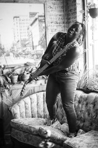 a black and white photo of a woman playing a guitar on a couch
